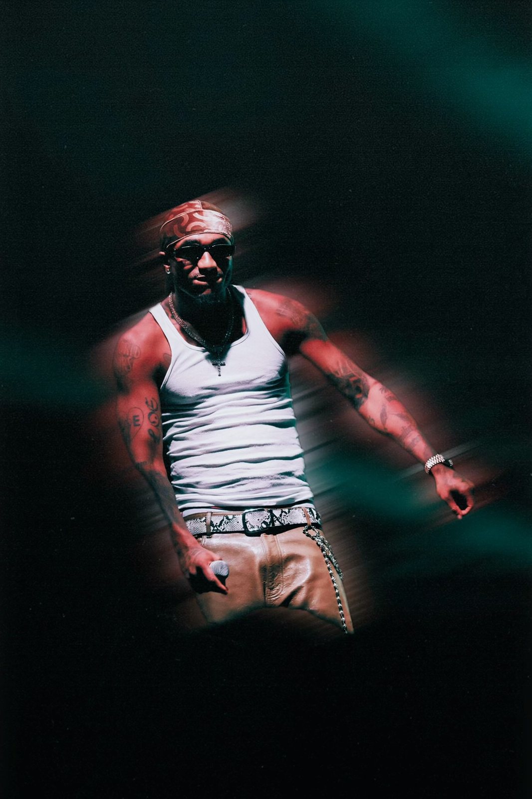Performer in a white tank top caught in red and teal stage light