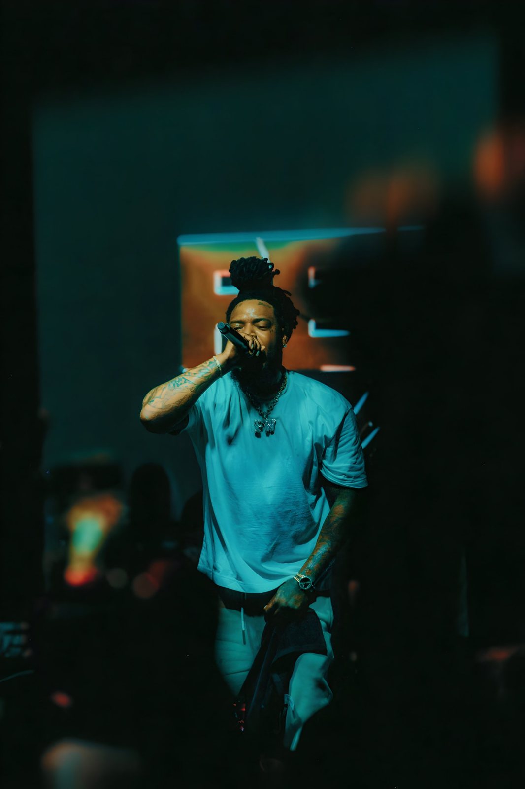 Performer rapping into a mic under teal stage light